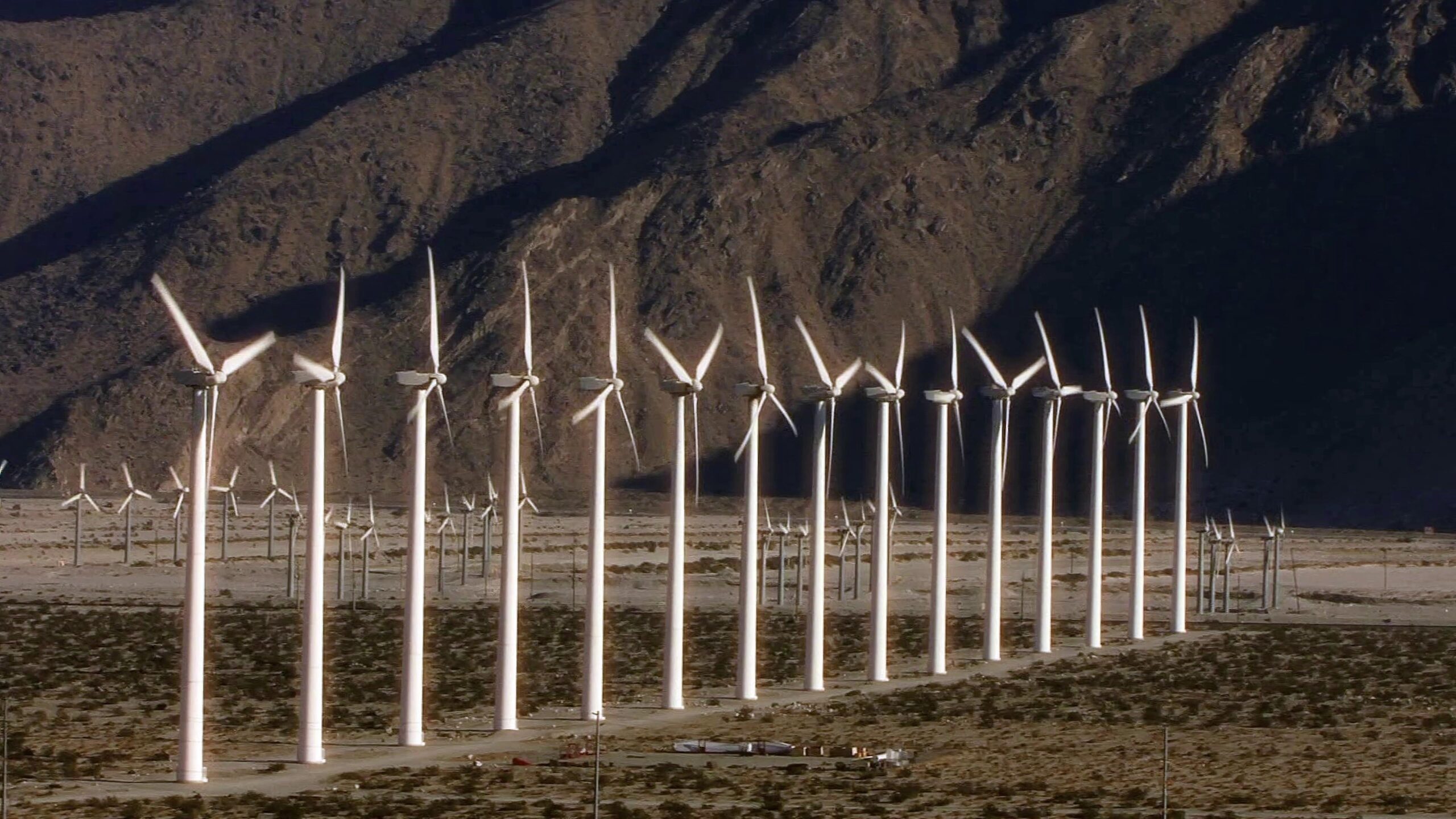 4K video of rows of wind turbines generating clean energy in arid mountain valley