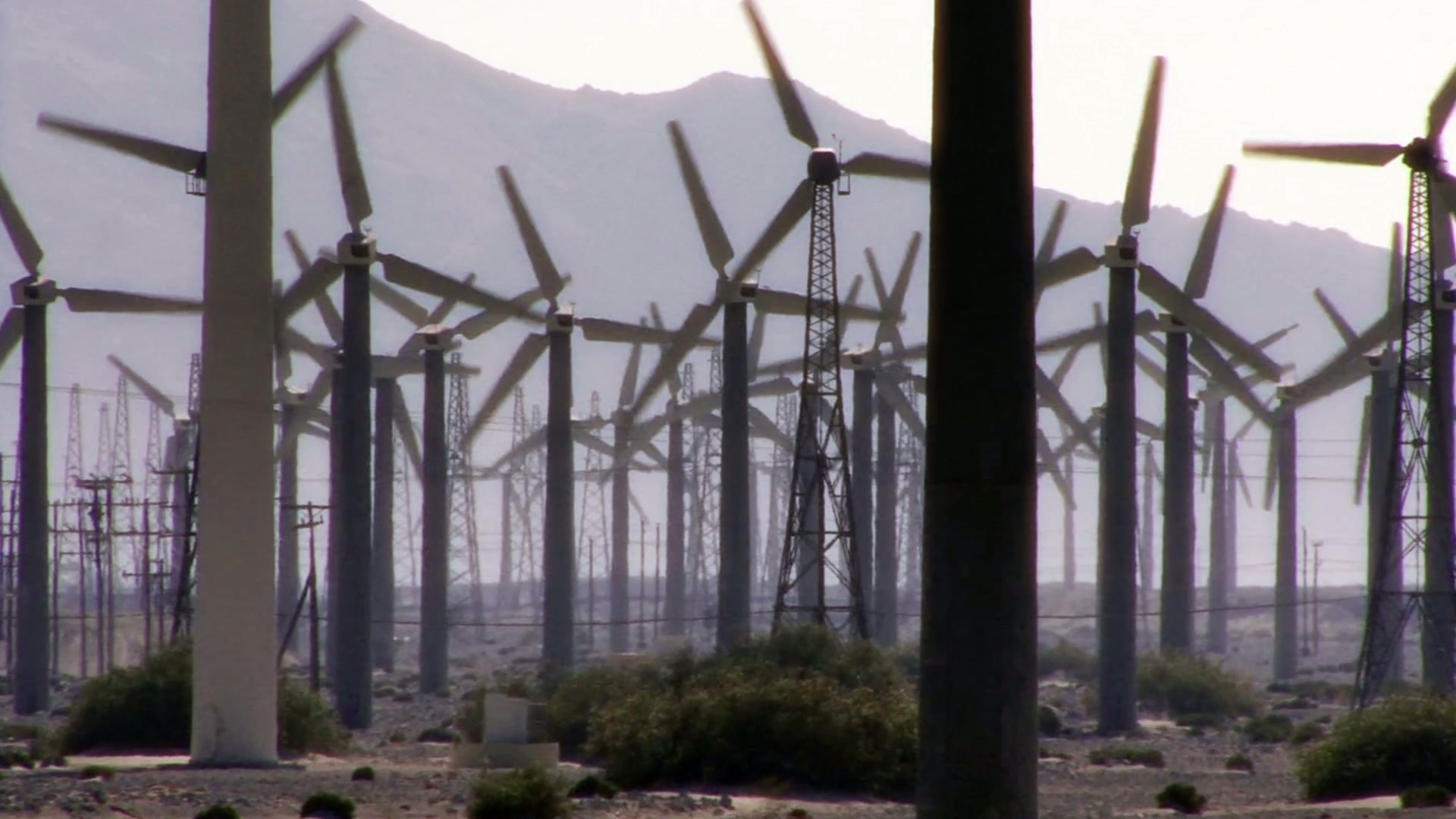 The video depicts a vast wind farm set against a mountainous backdrop.