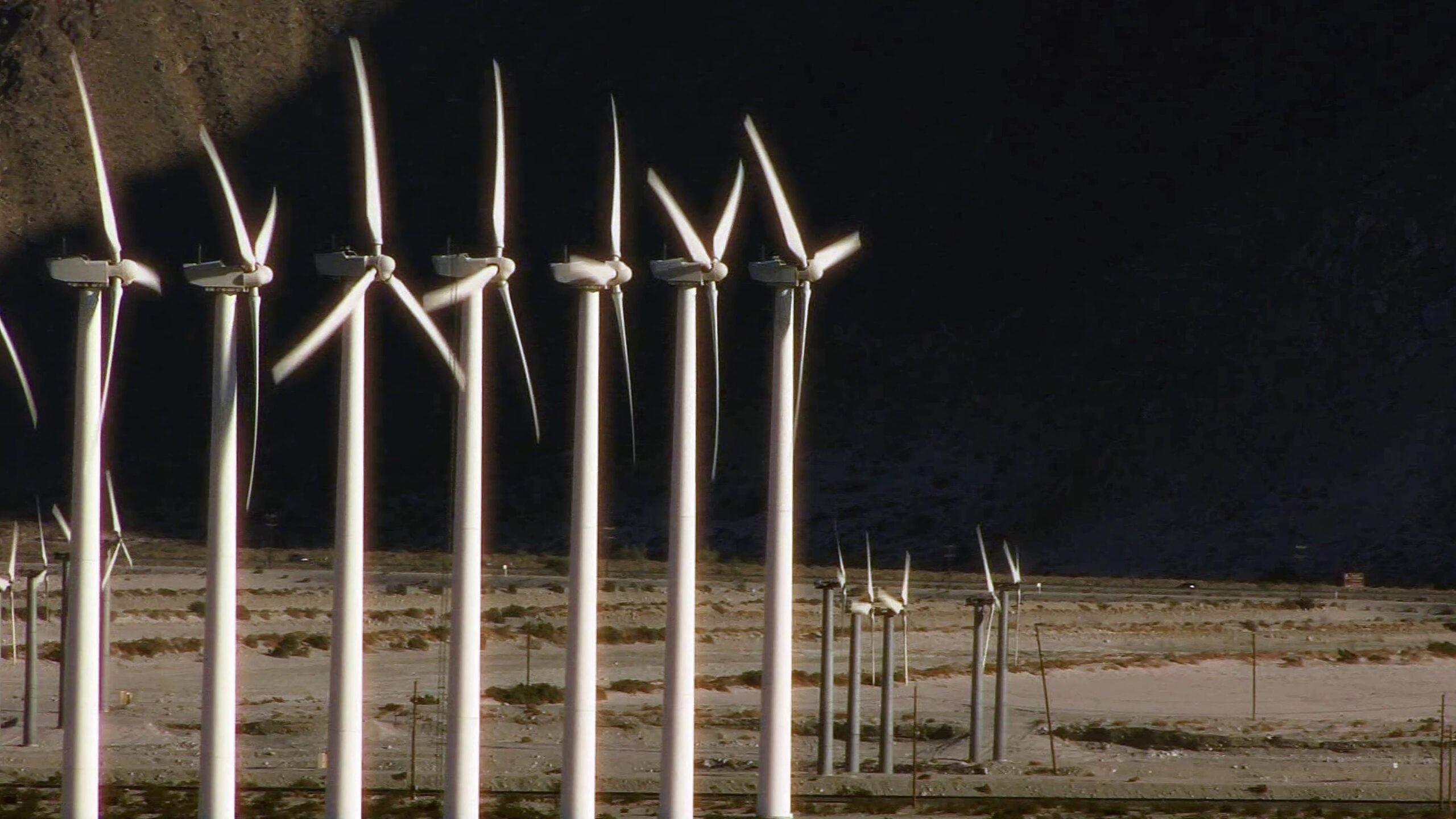 White wind turbines spinning in desert landscape