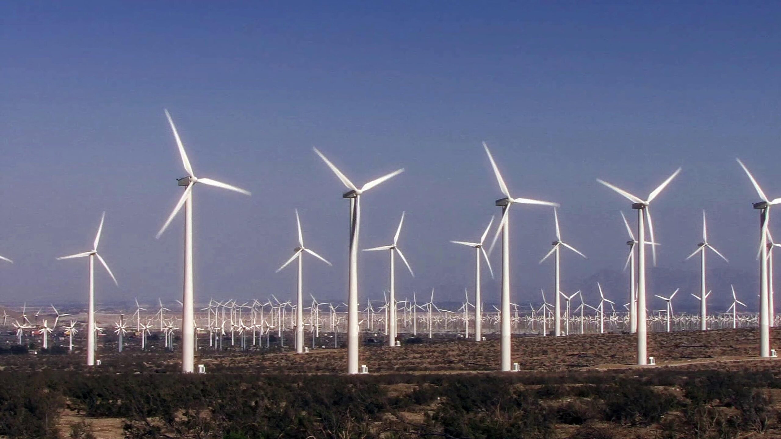 4K video of operational wind turbines generating green energy in open desert plains