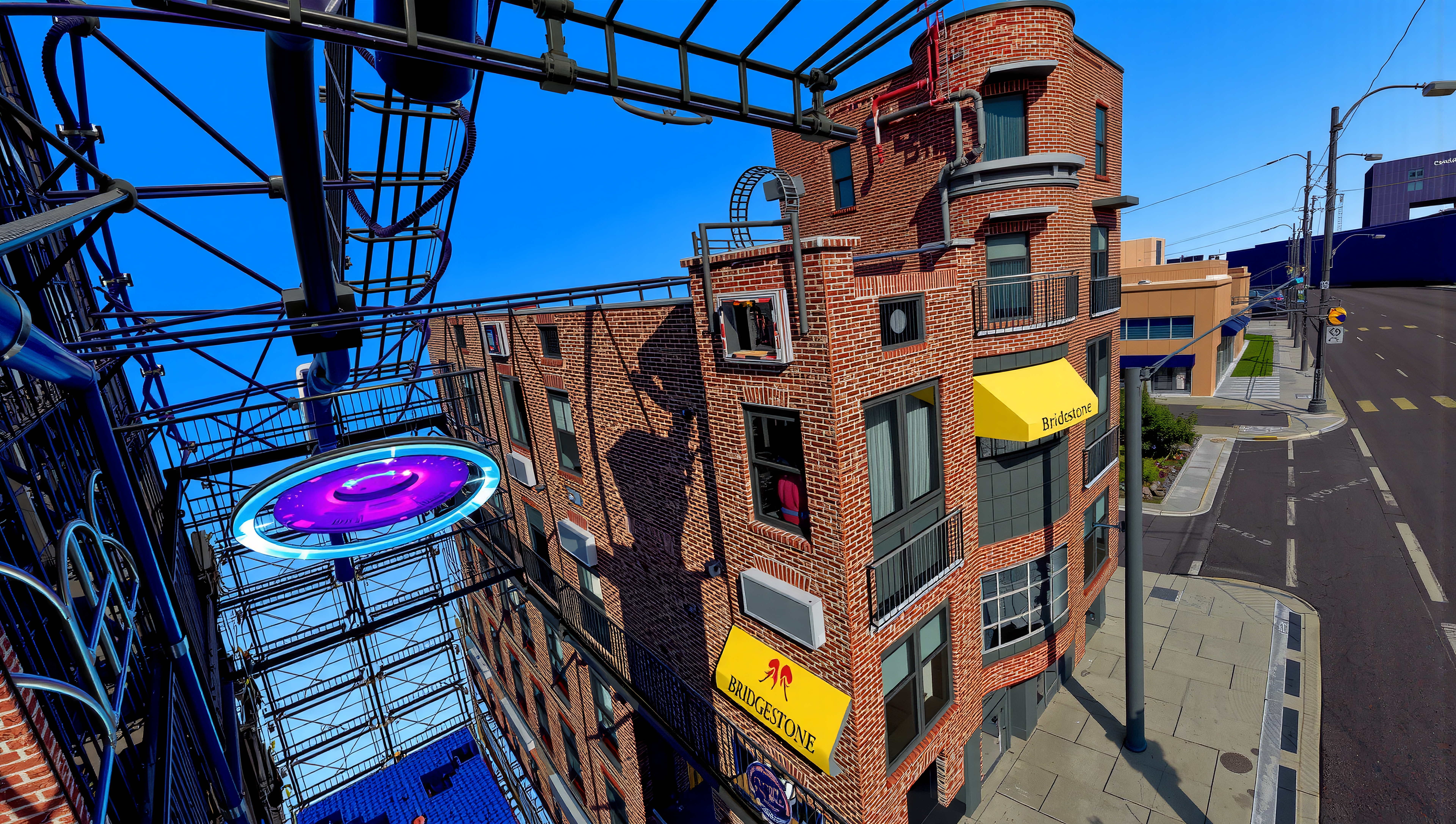 A brick building with a futuristic structure under a bright blue sky in a cityscape.