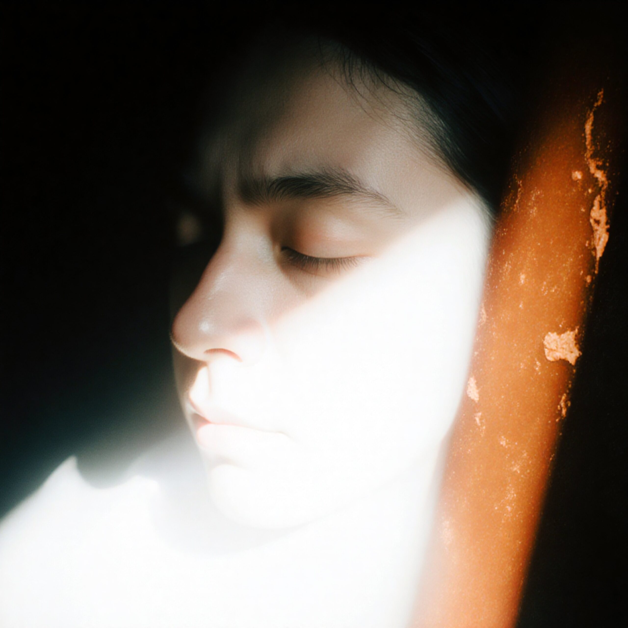 A serene close-up portrait with dramatic light and shadow contrasts.