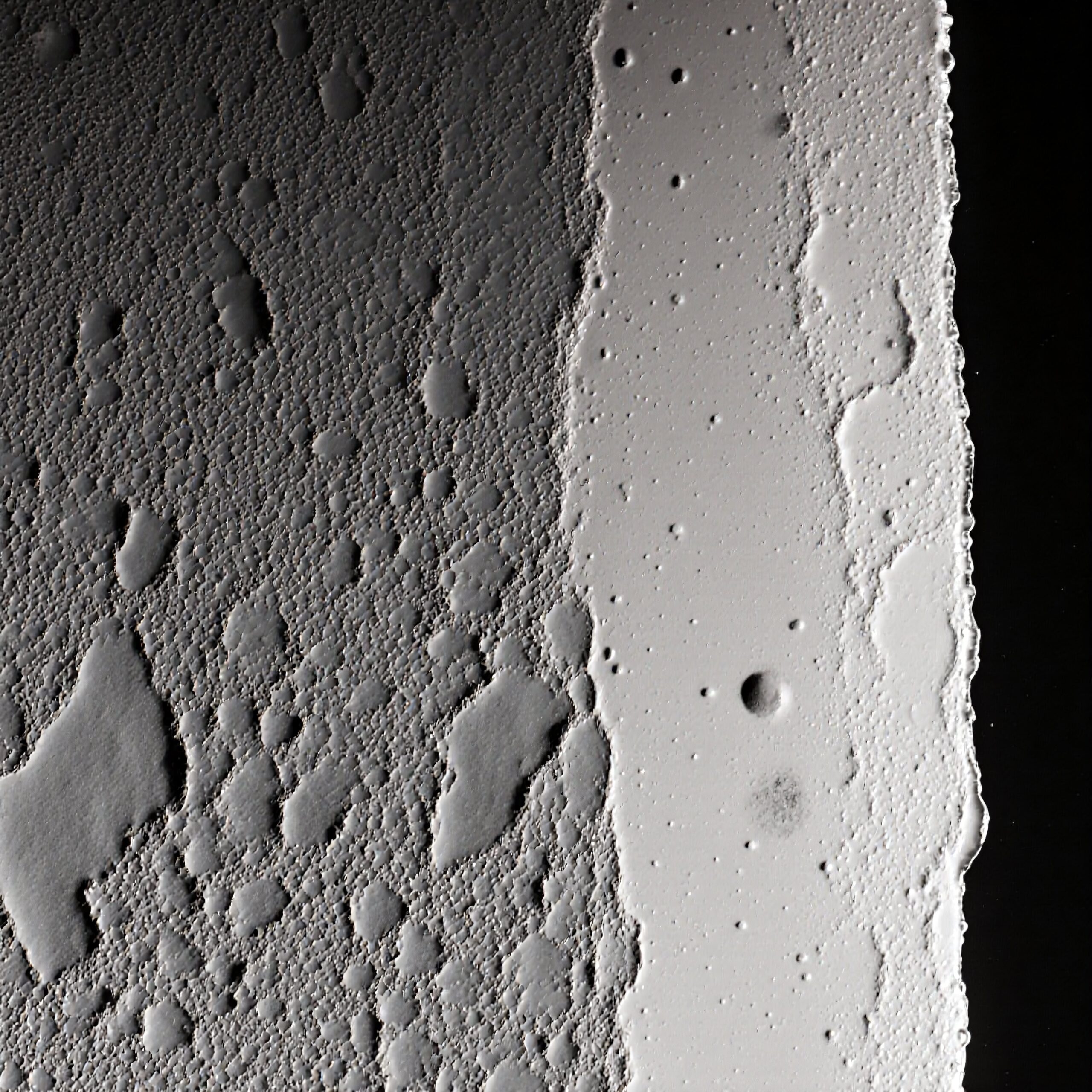 Close-up of a textured lunar-like surface with craters.