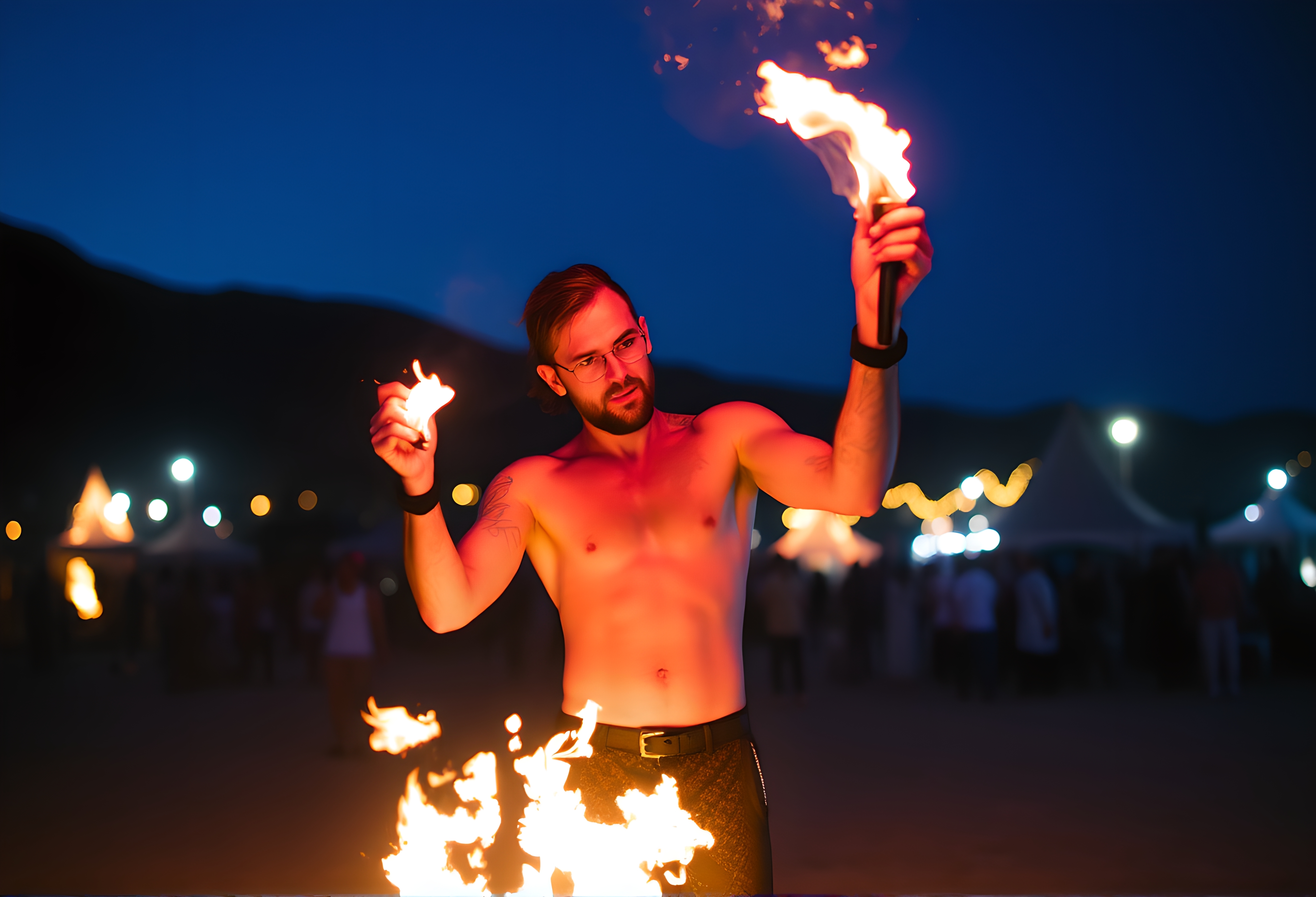 A shirtless fire performer skillfully manipulates fiery torches against a vibrant night sky, captivating an outdoor event crowd.