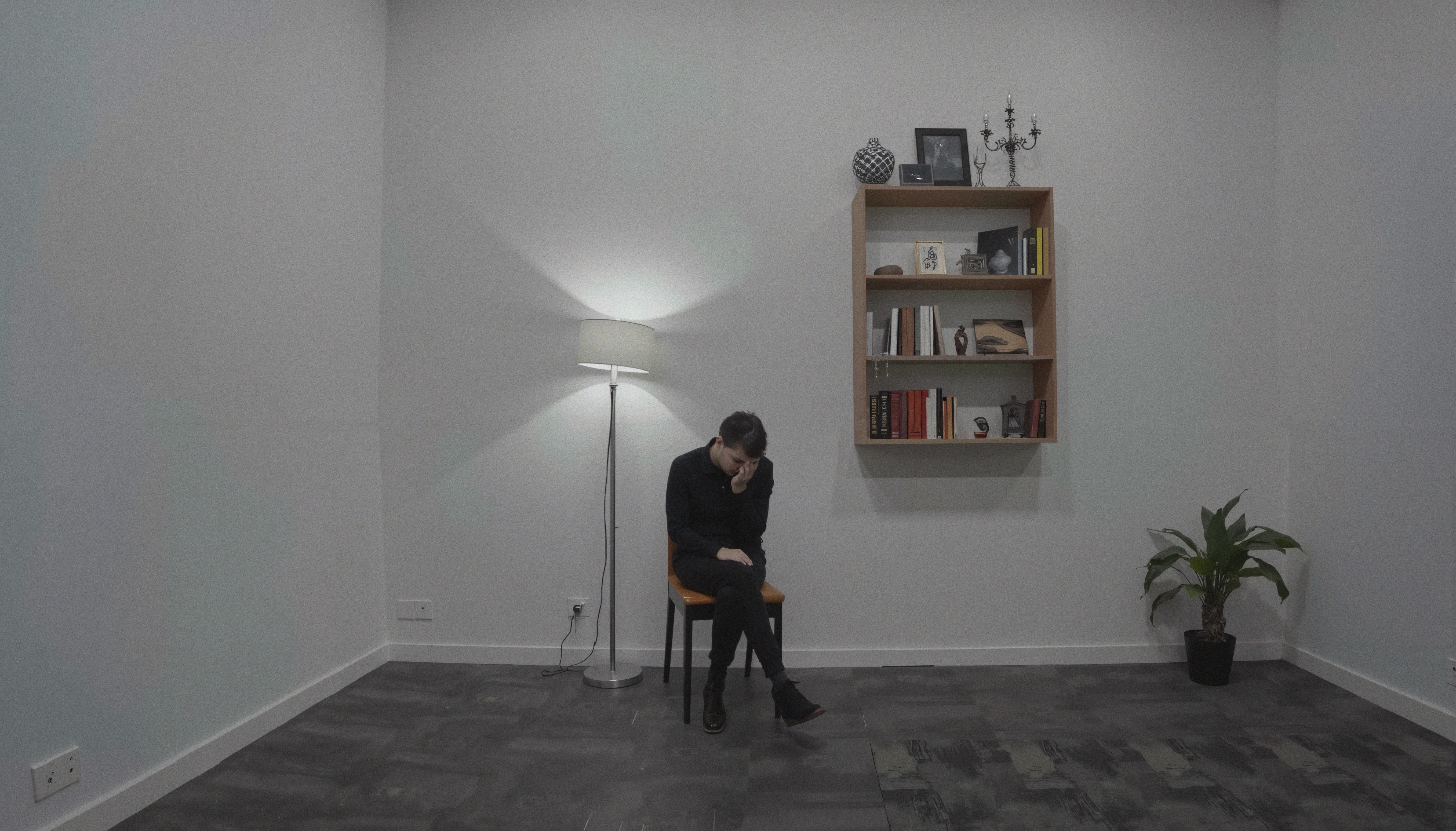 A person sits alone in a minimalist room, conveying solitude.