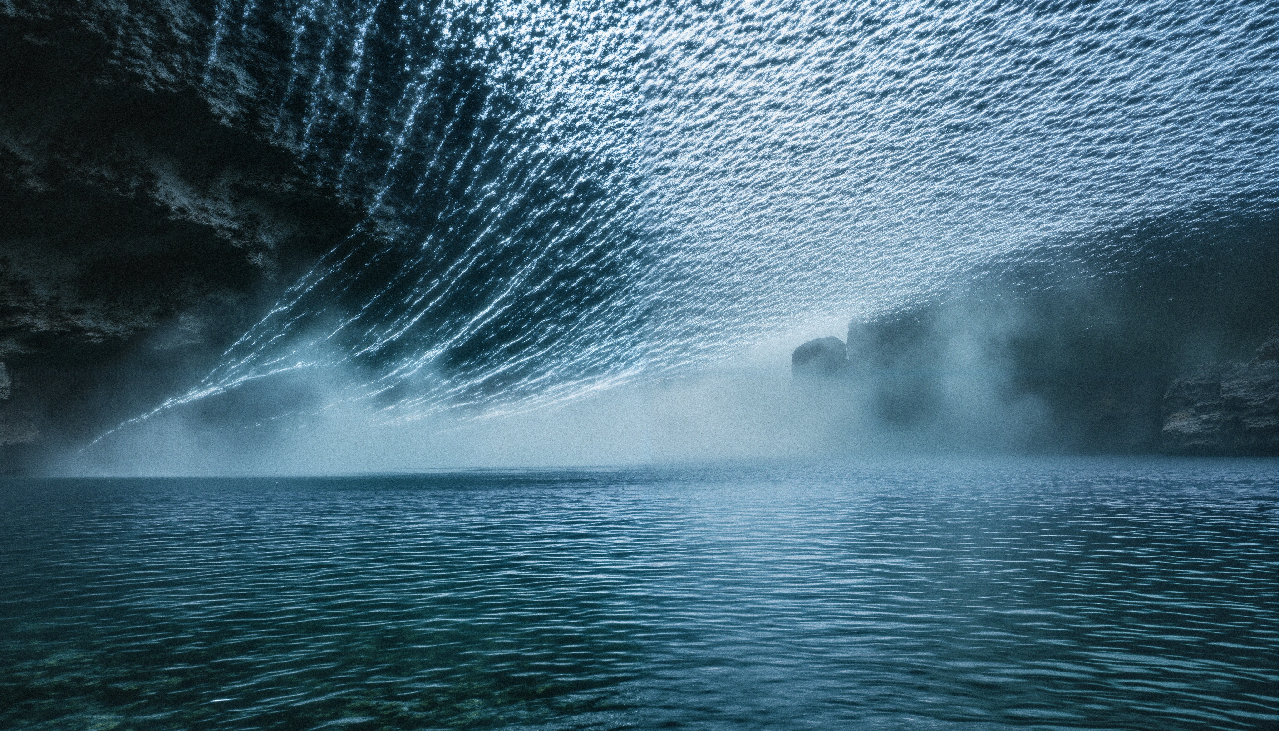 Dramatic seascape with inverted waterfall effect over a misty lake surrounded by cliffs.