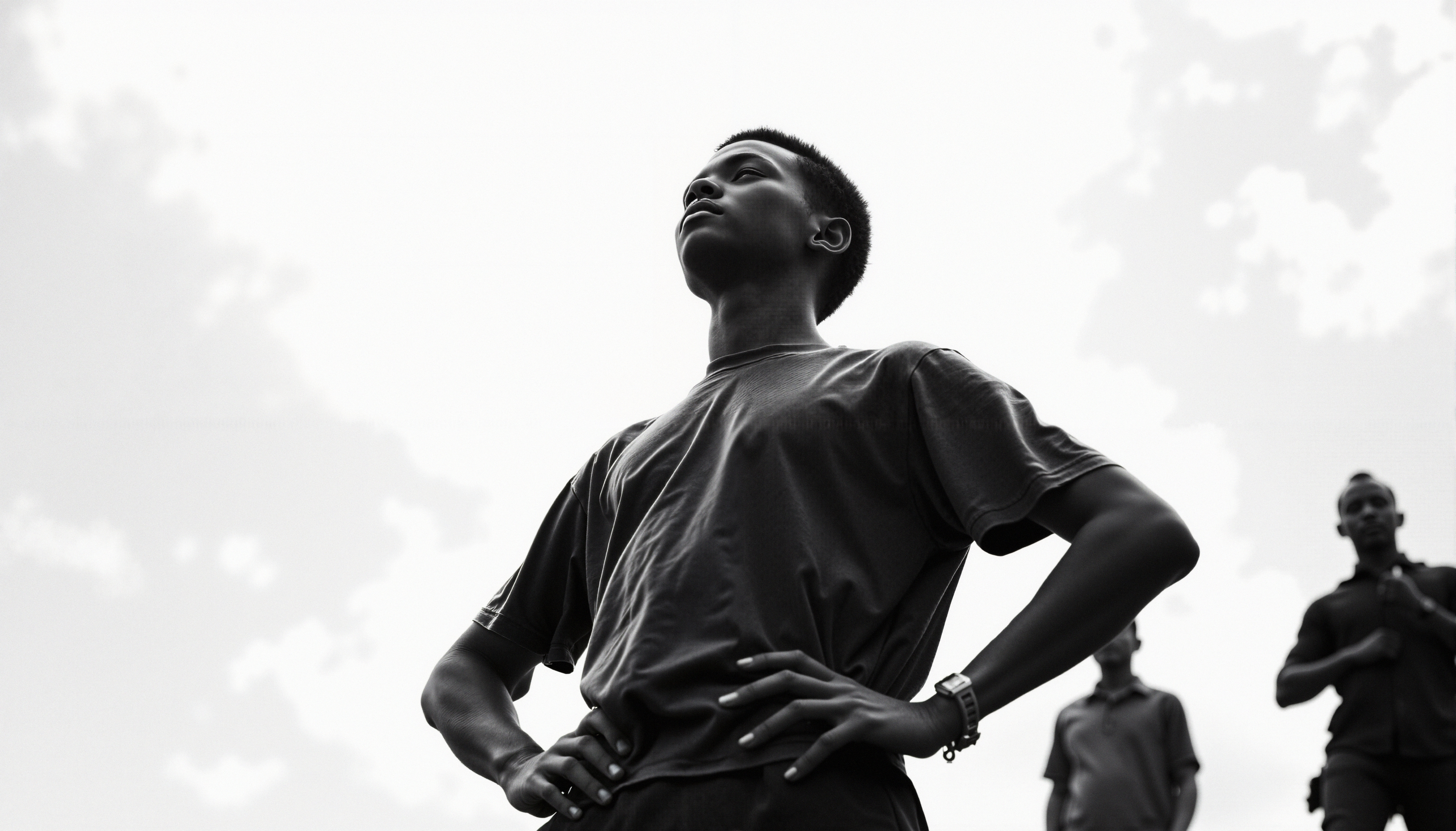 A black-and-white image of a confident young person gazing upwards against a bright sky, embodying empowerment.