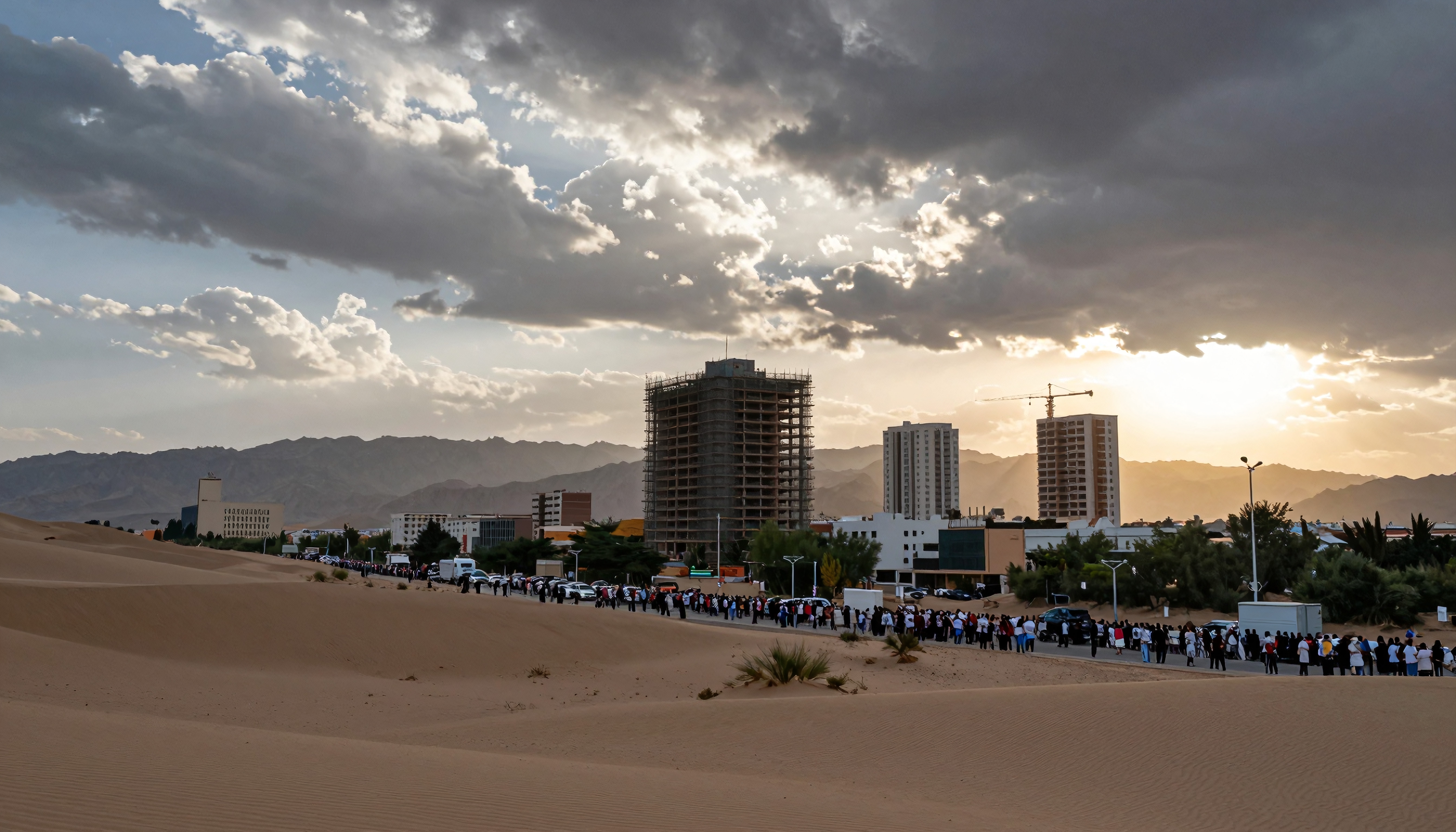 A large group lines up in a desert city during sunset, under a dramatic cloud-filled sky.