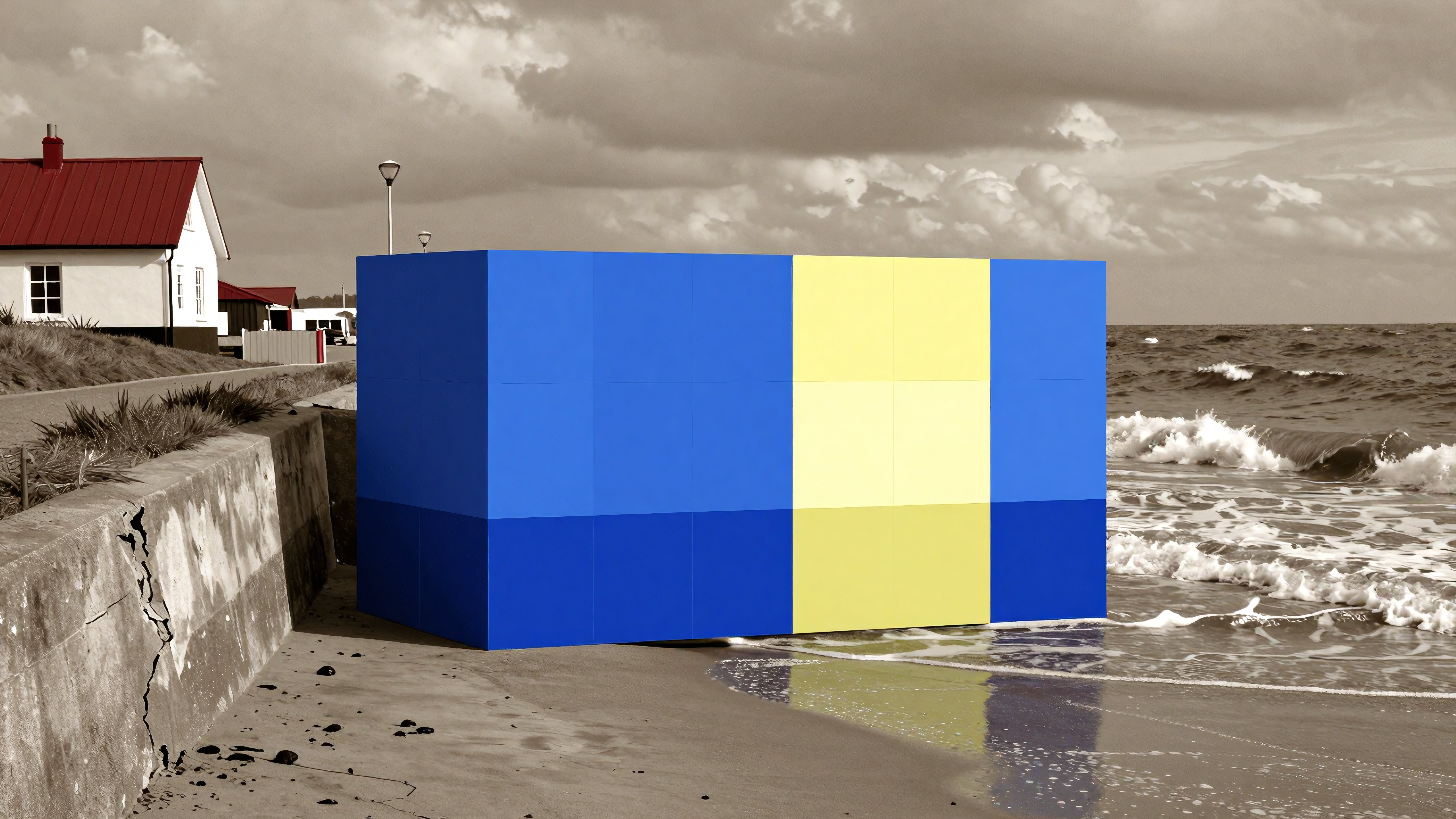 Modern colorful cube sculpture on sandy beach next to ocean waves and houses