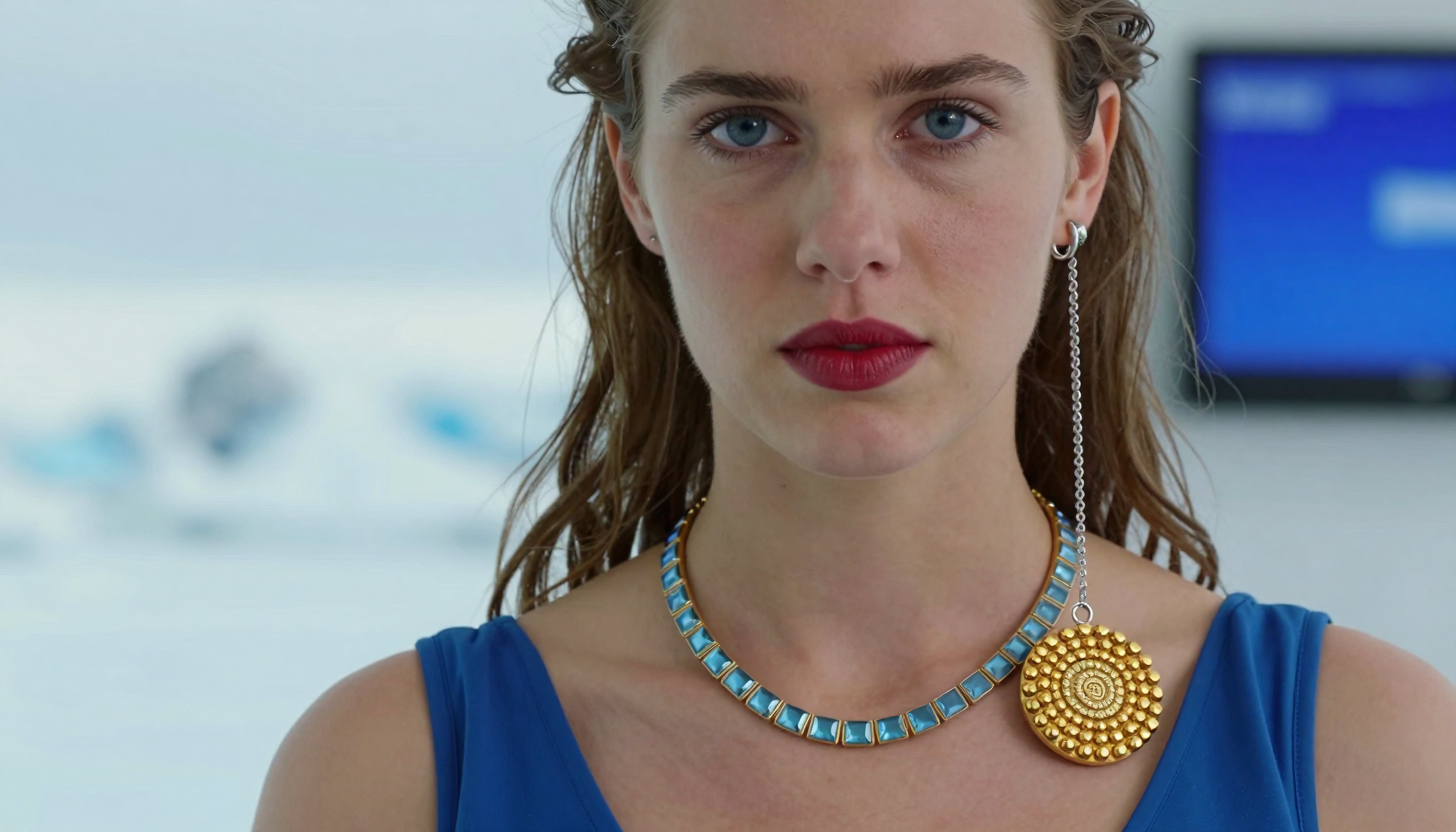 Woman wearing luxurious gold necklace and red lipstick near snowy landscape