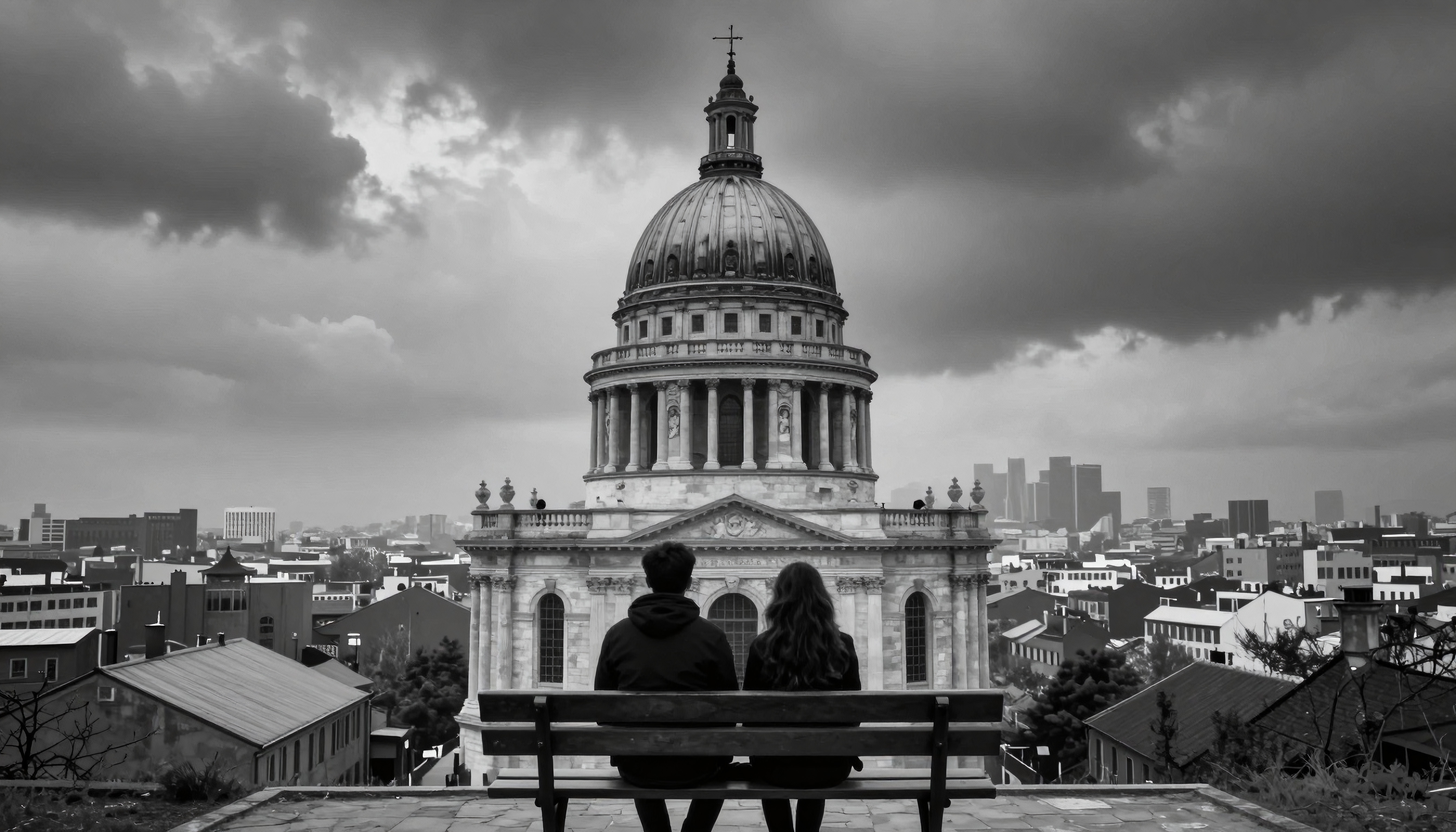 Black and white image of a couple sitting on a bench viewing a large domed building amidst a contrasting city skyline.