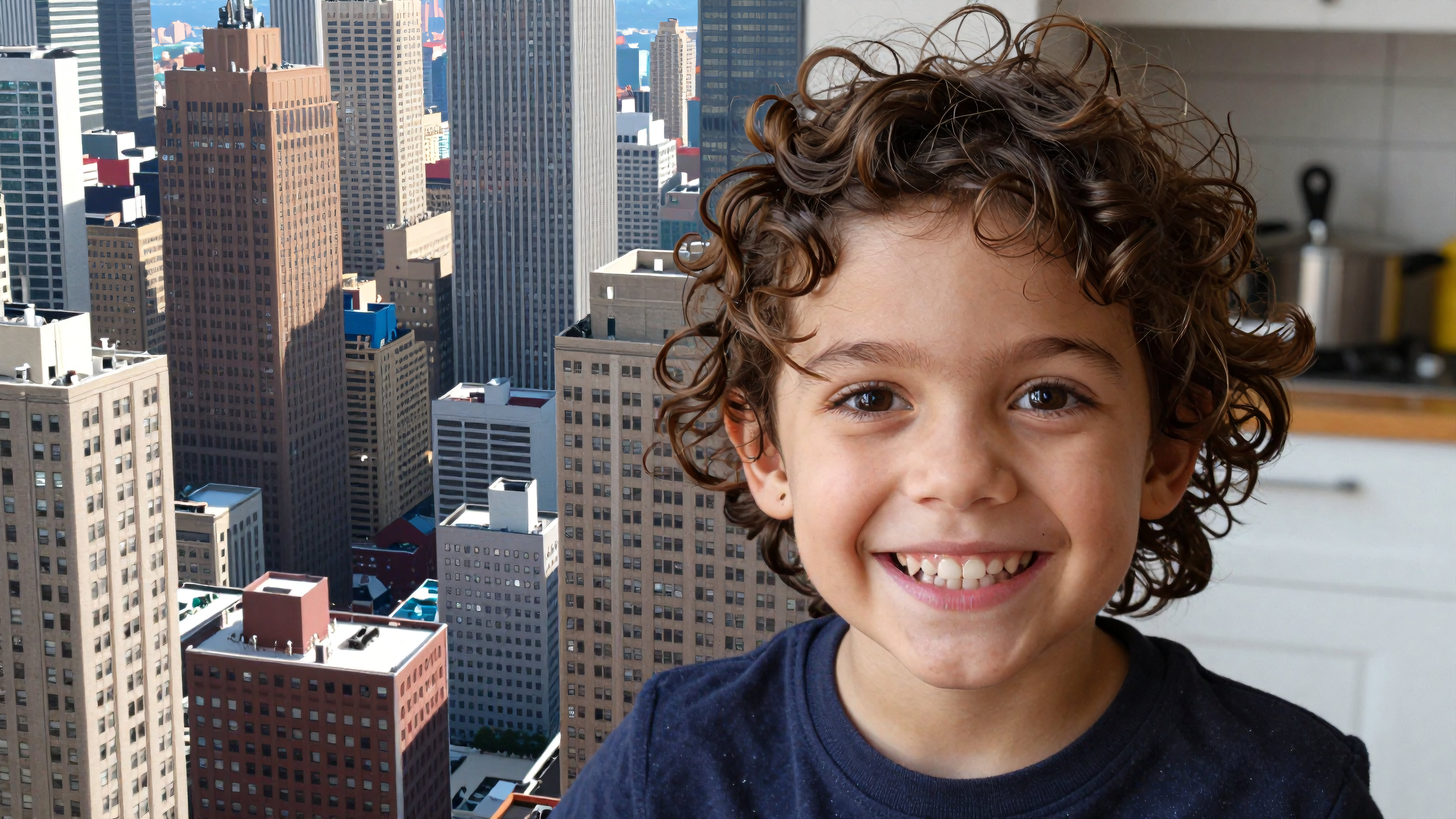Cute smiling boy with curly hair posing inside apartment overlooking busy city skyline