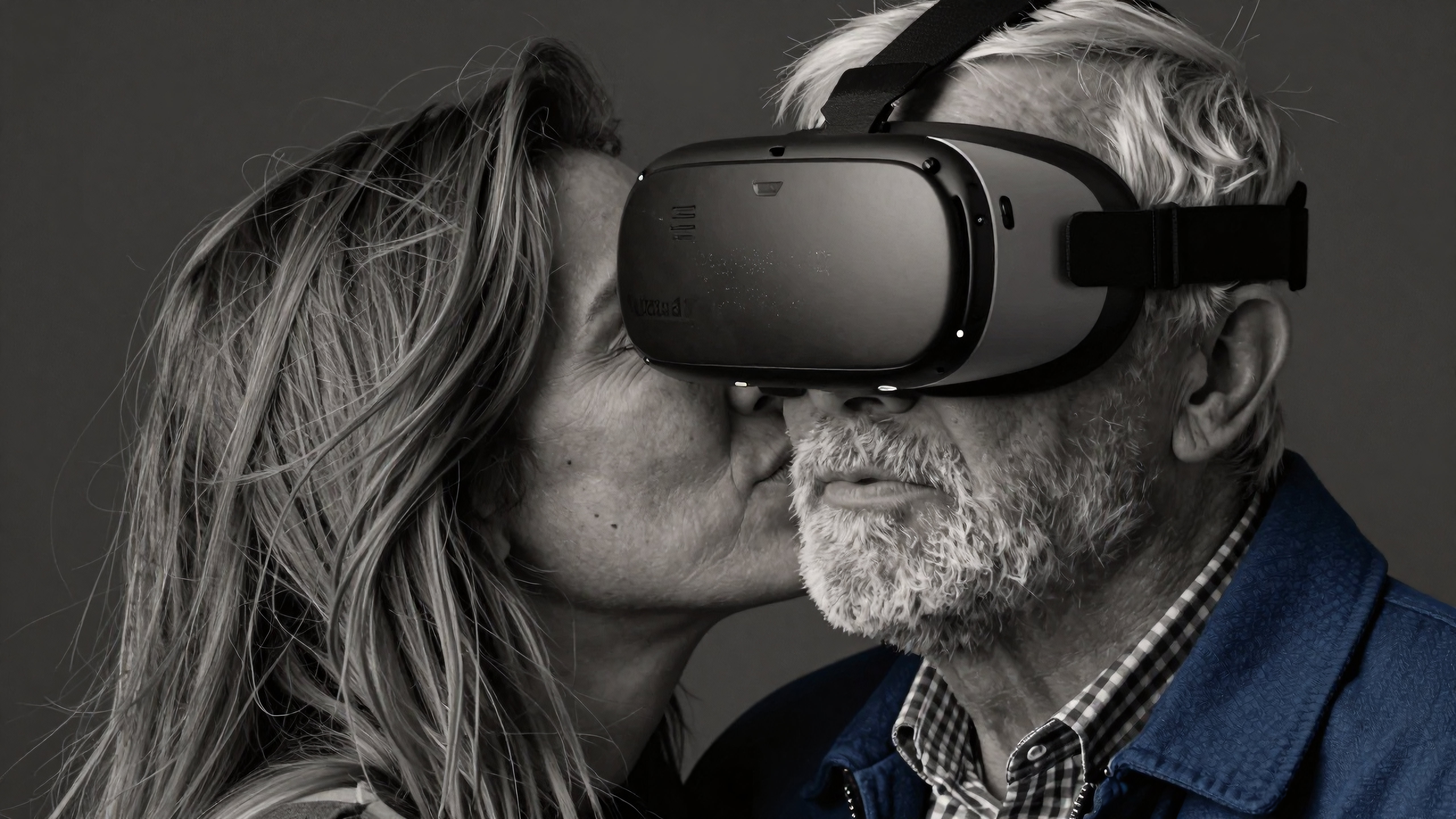 Elderly man wearing VR headset kissed by loving partner embracing futuristic technology