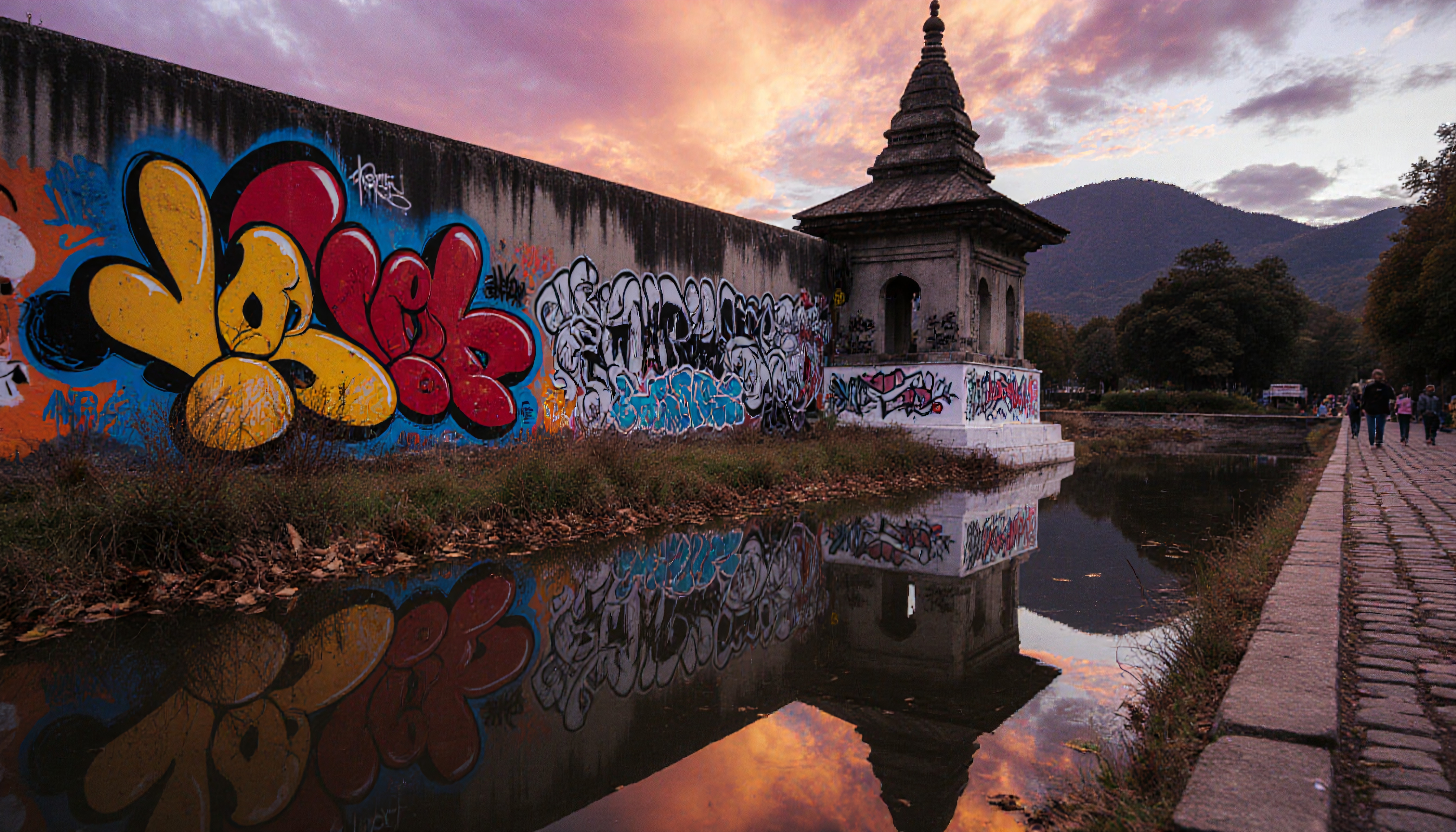 A vibrant sunset reflects vivid graffiti and traditional architecture along a tranquil waterway, capturing an urban scene.
