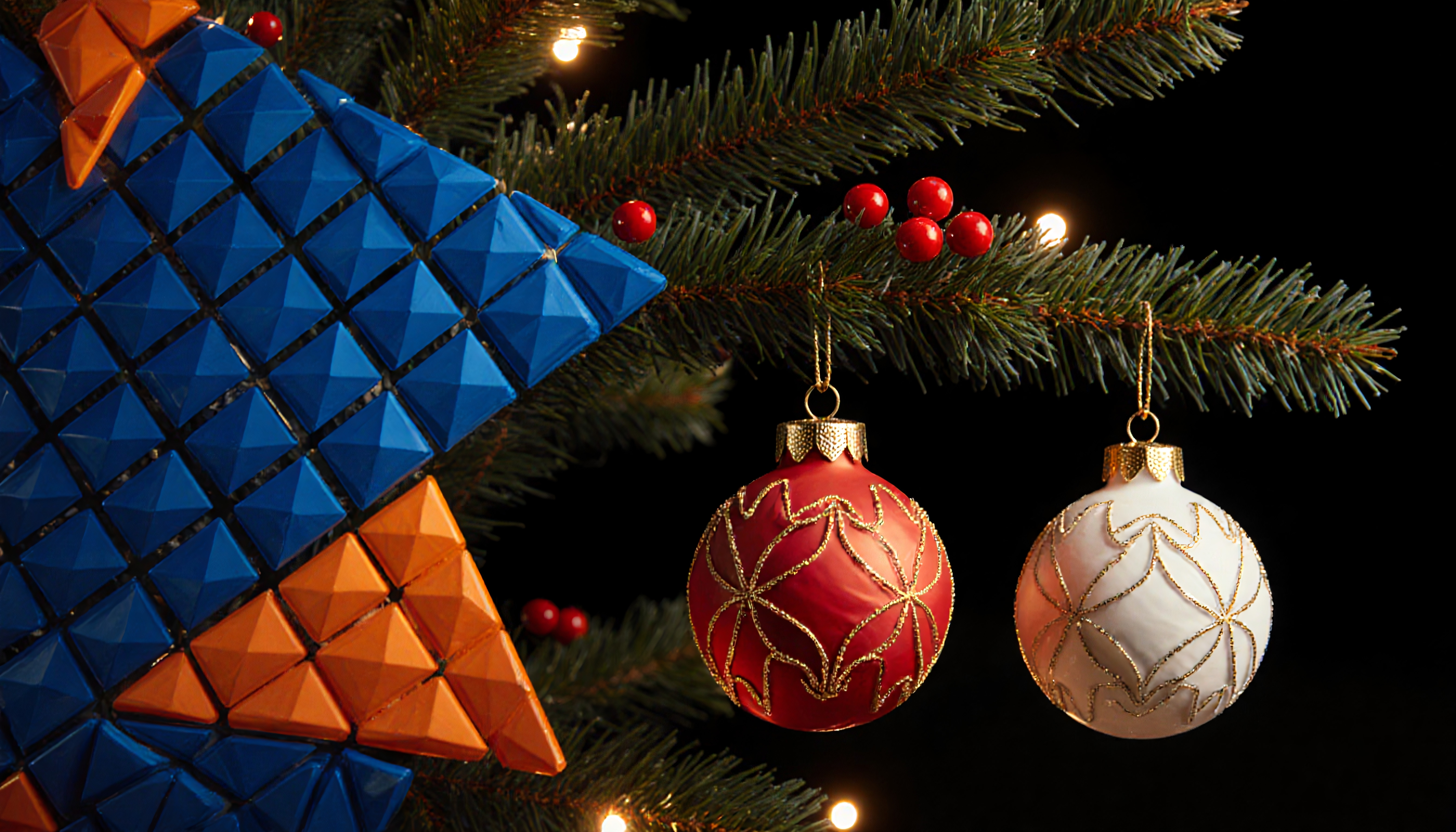 Two decorative Christmas baubles on a beautifully illuminated tree branch.