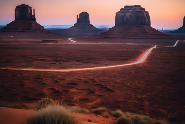 Sunset desert road winding between towering rock formations