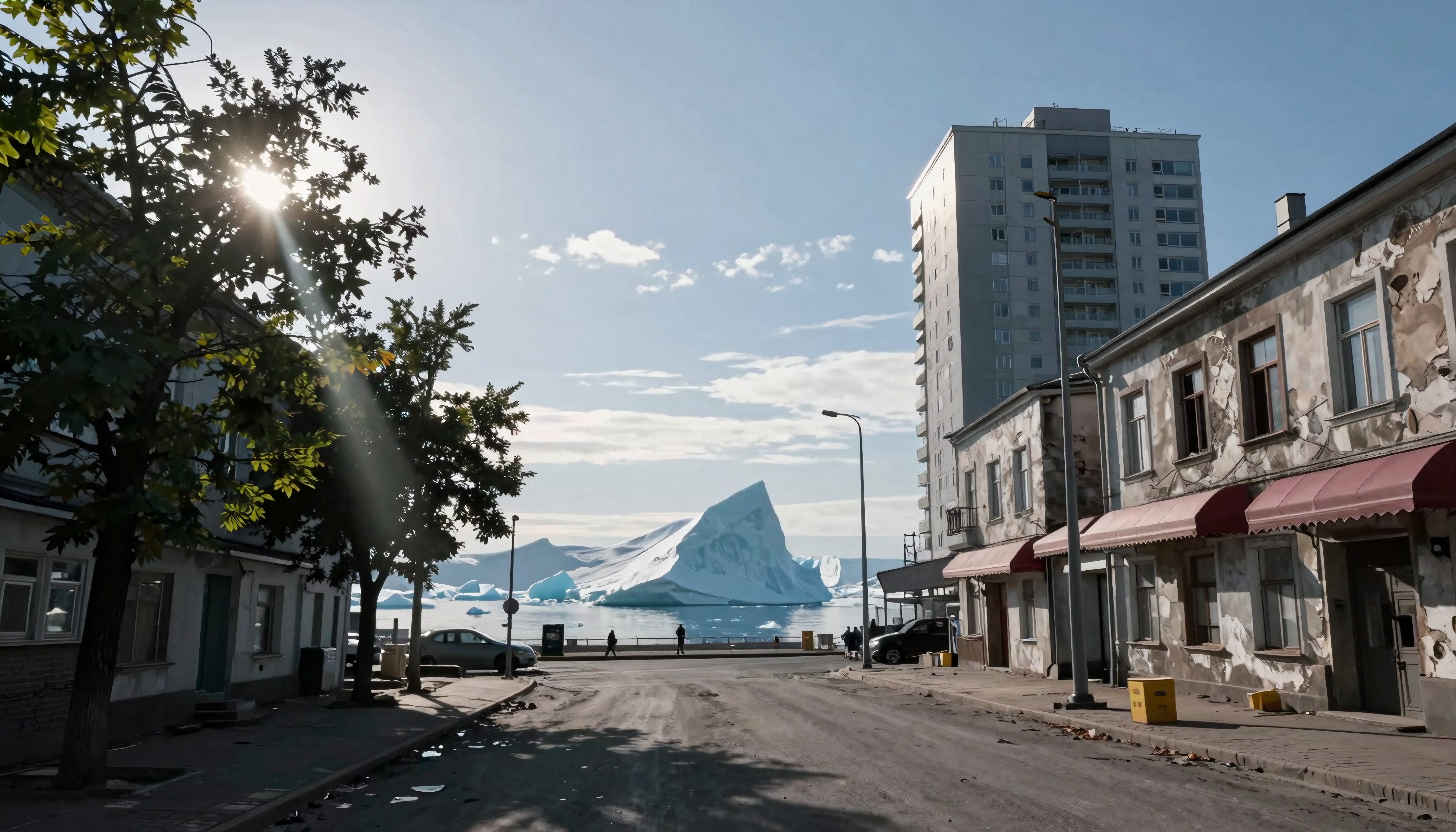 A quiet urban street with trees and buildings leads to an ocean view with a large iceberg in the distance.