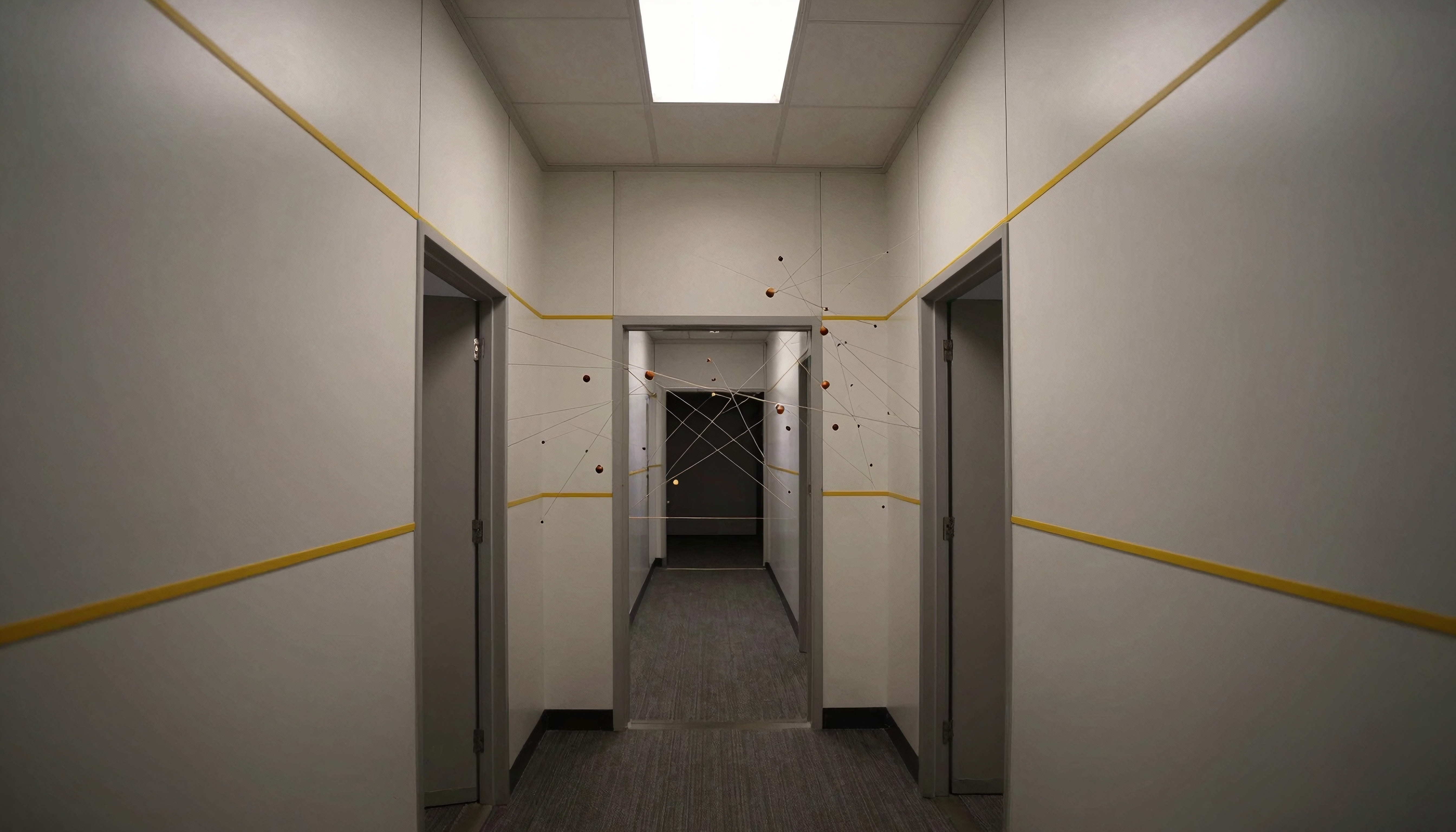 A minimalist hallway with geometric art installation of spheres and wires.