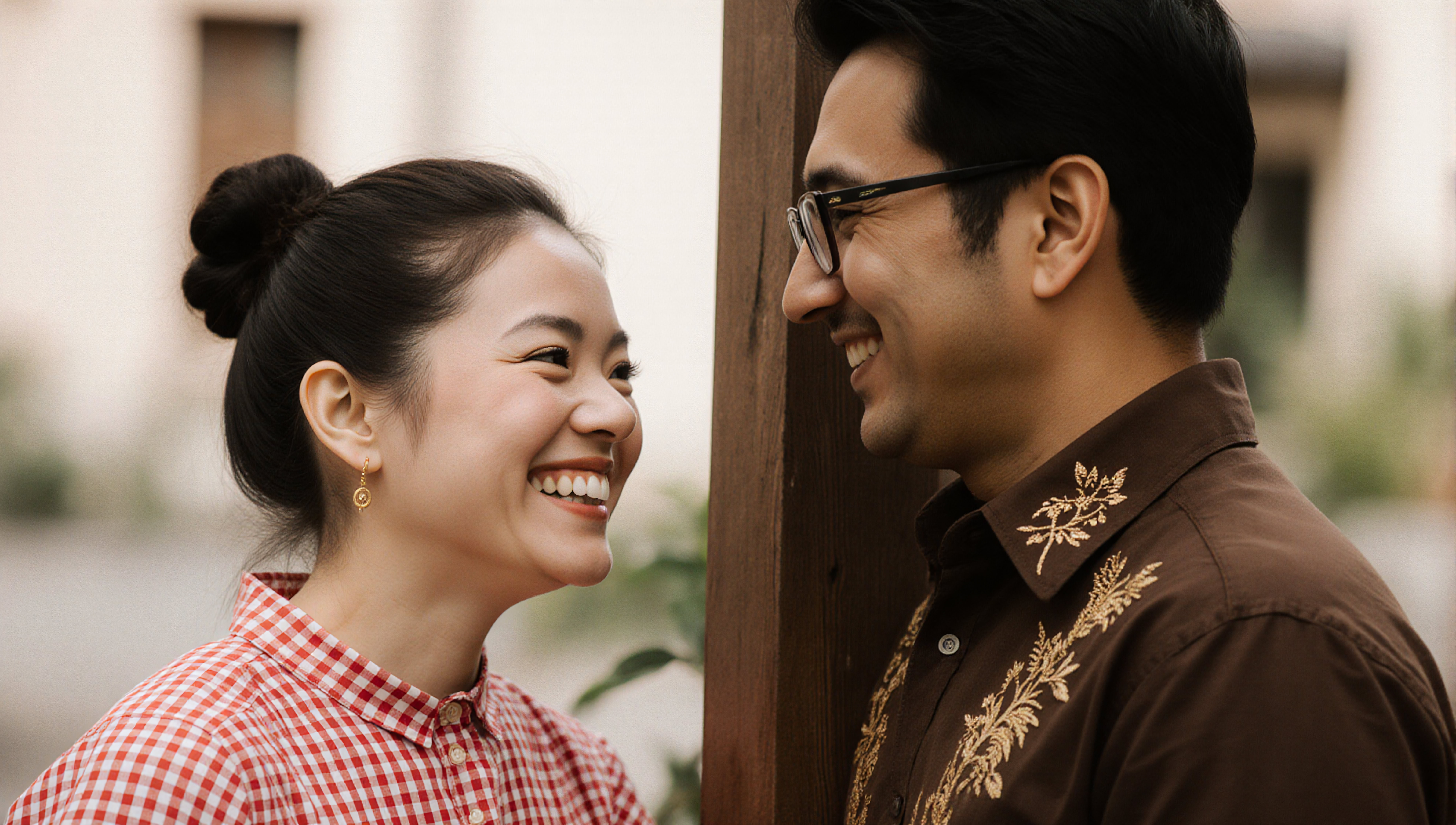 Happy smiling Asian couple laughing together outdoors near wooden fence
