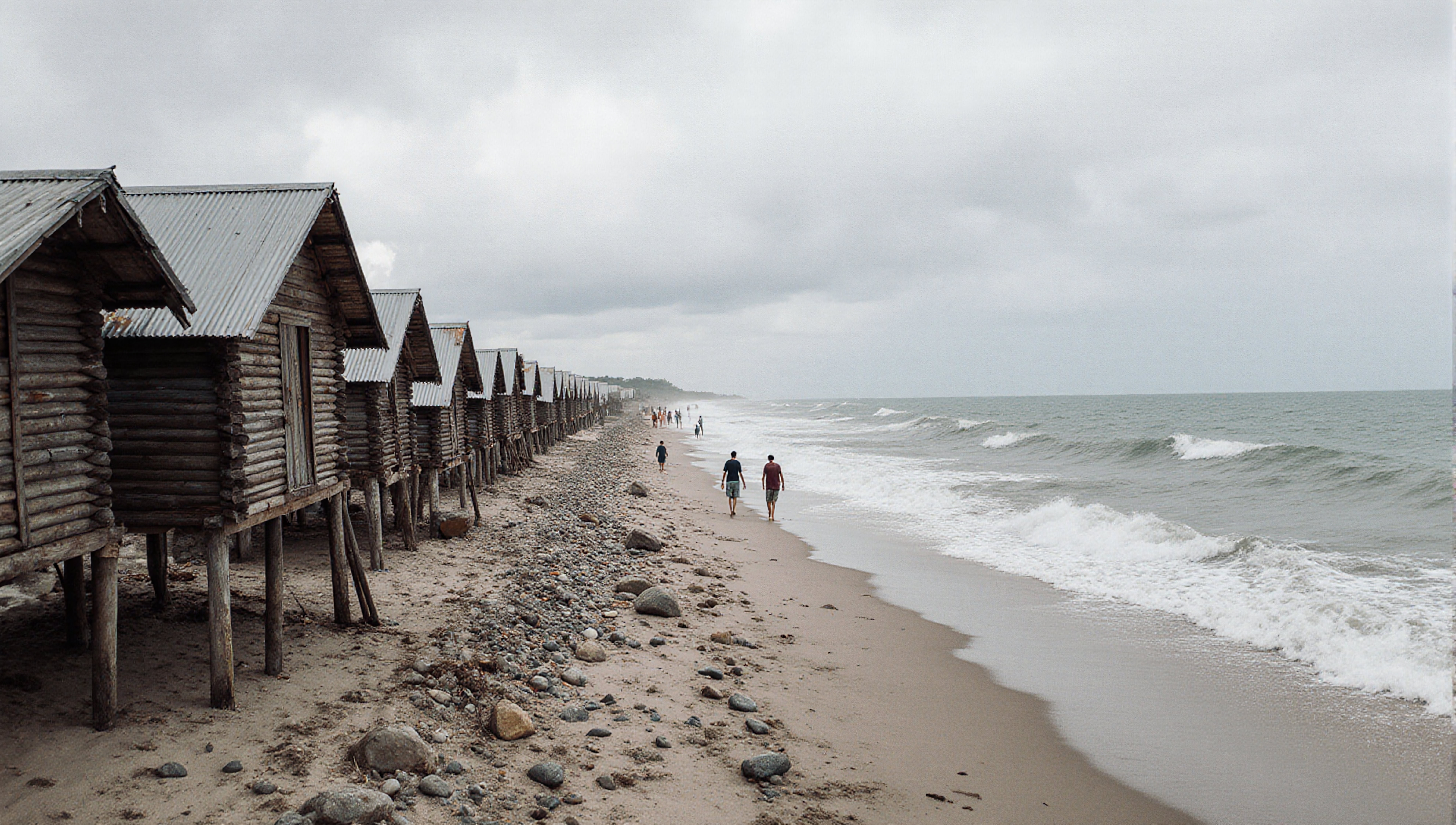 Rustic huts line a rocky beach.