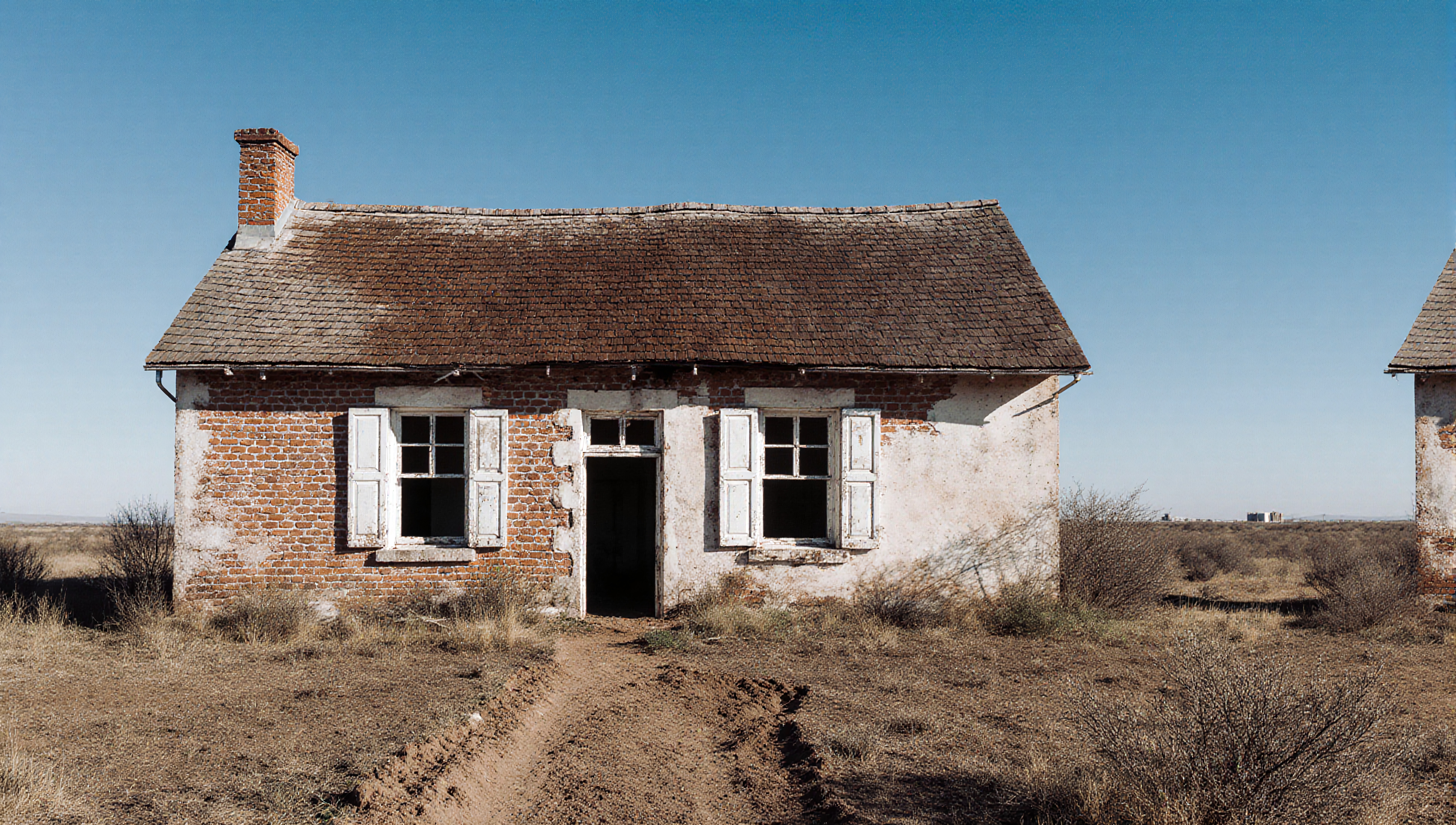 Old abandoned brick house in a desolate desert landscape.