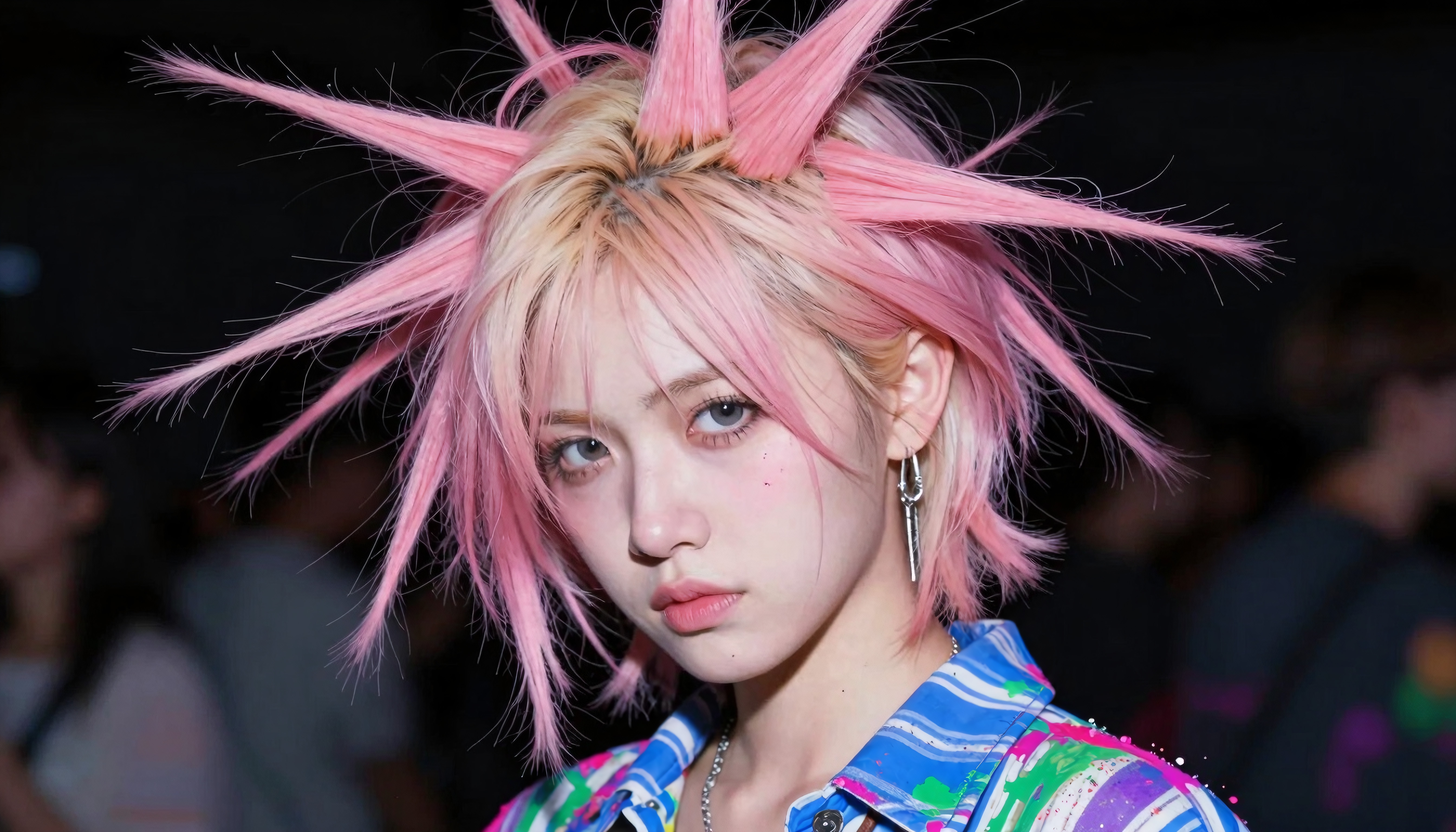 A person with bold pink spiky hair and a colorful shirt showcasing a unique fashion style.