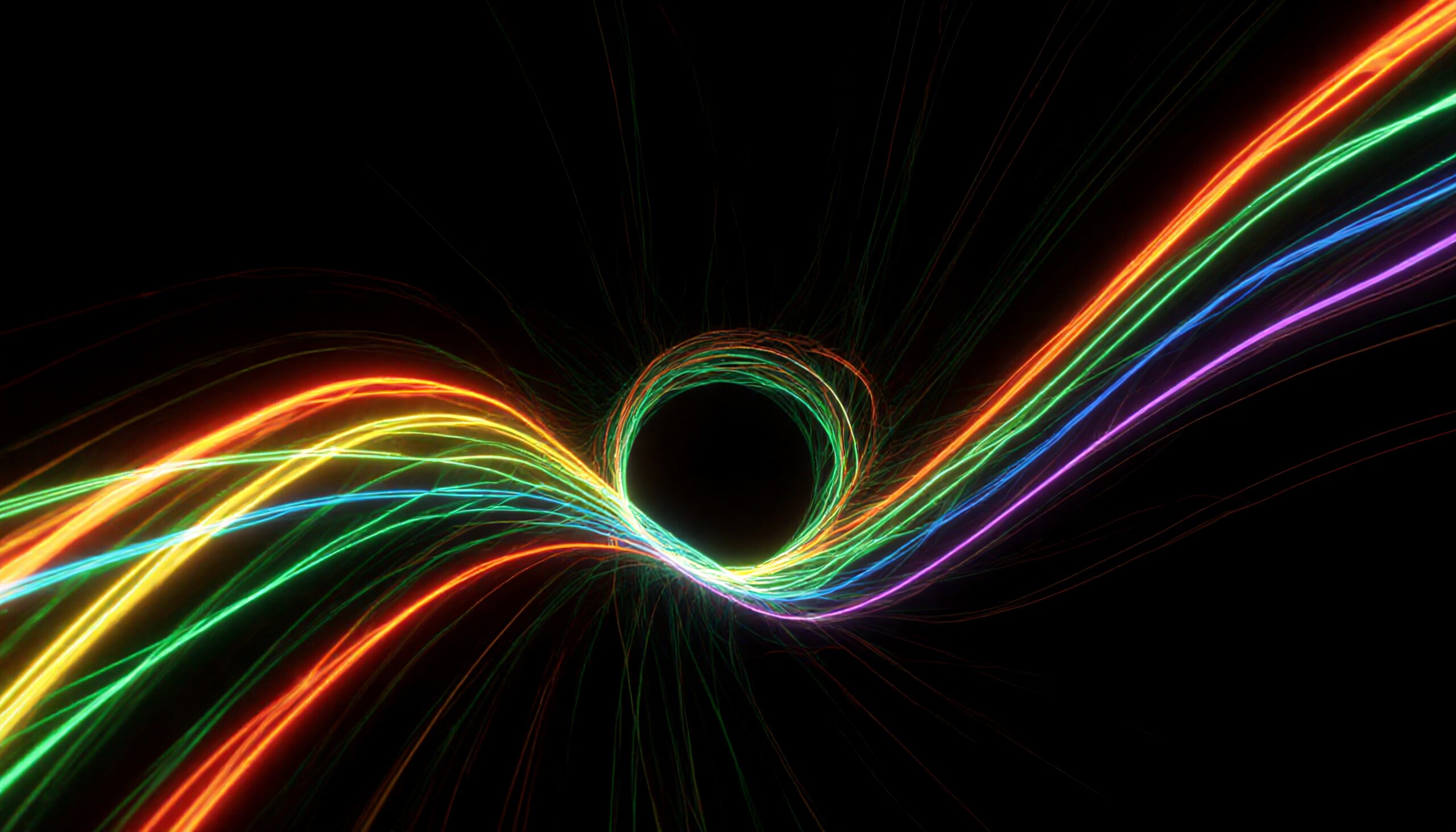 Multicolored light trails forming a vortex, swirling energies around a dark center against a black background.