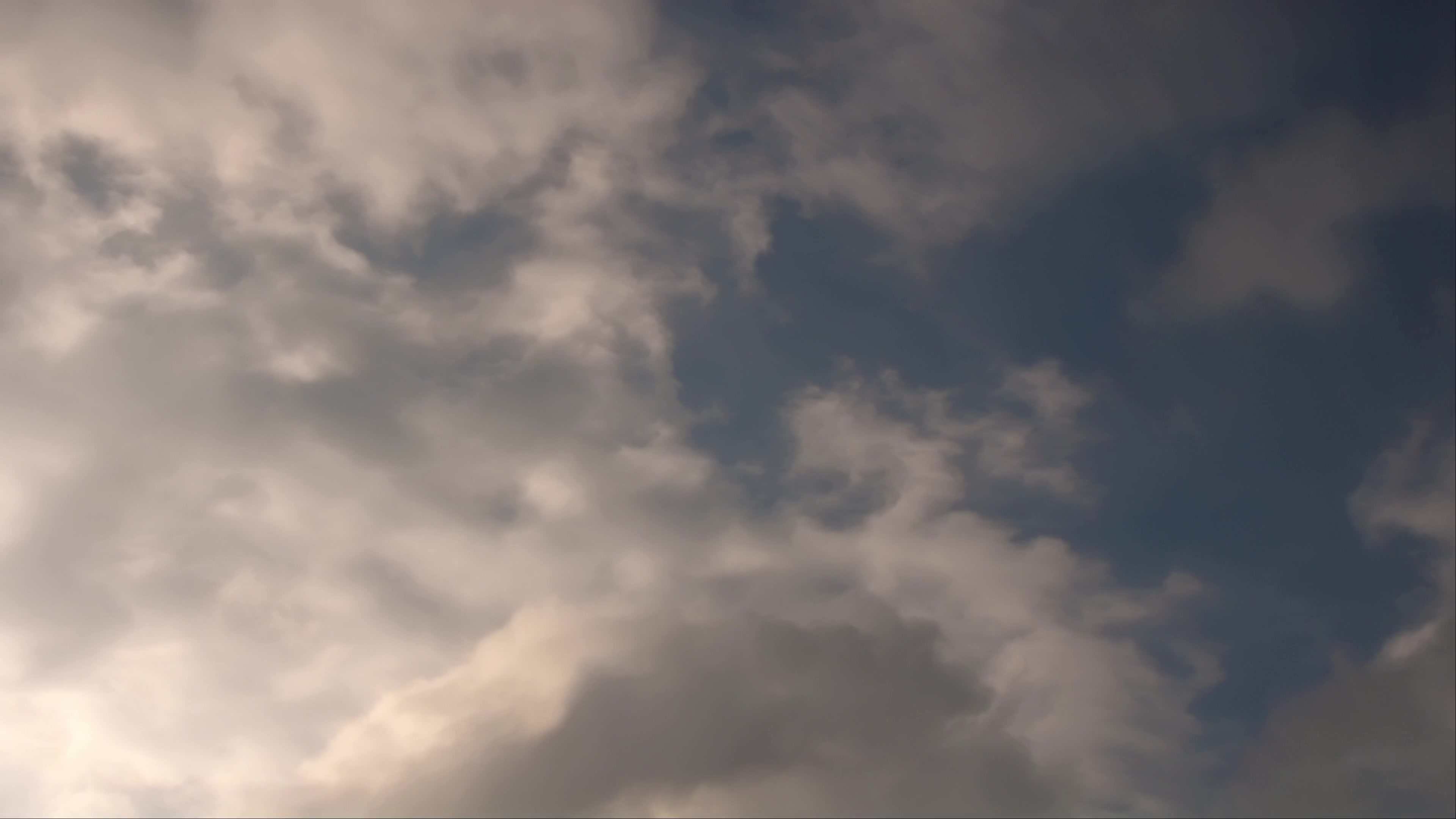 Serene sky with fluffy clouds in varying shades of white and gray, providing a calming view against a backdrop of blue.